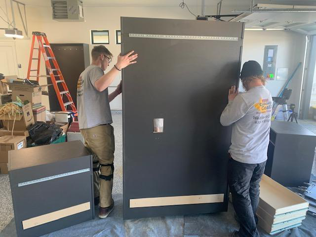 Two people marking outlet location on cabinet